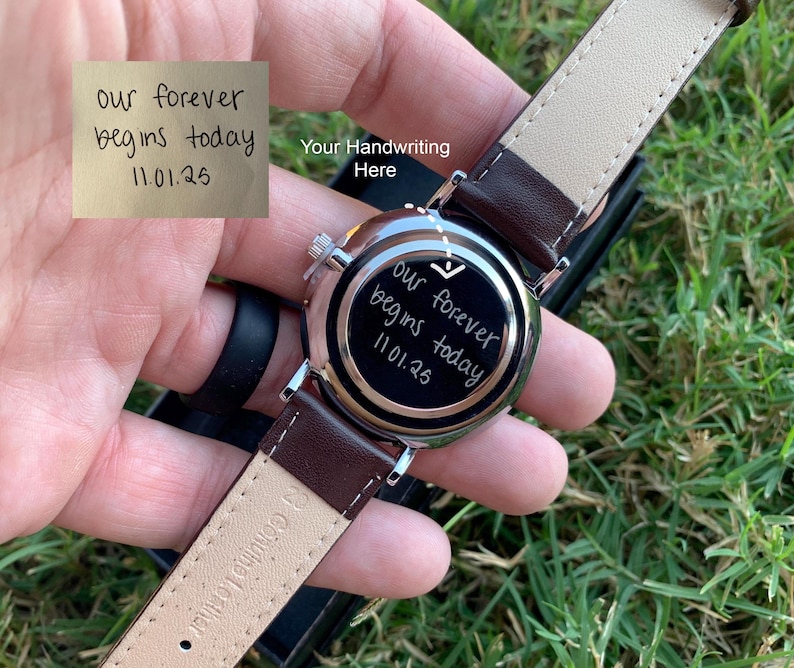 May include: A wristwatch with a brown leather strap and a silver-colored case. The watch face has the inscription "our forever begins today 11.01.25". The words "Your Handwriting Here" are also visible.