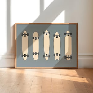 A framed illustration of five skateboards in various designs, displayed on a wooden floor against a white wall.