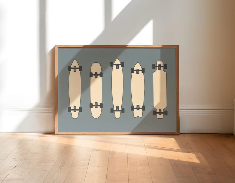 A framed illustration of five skateboards in various designs, displayed on a wooden floor against a white wall.