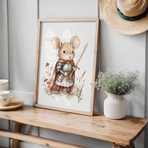 a mouse dressed in a knight's armor, holding a sword and standing in a grassy field with flowers. The mouse is the central focus of the image, which is framed and displayed on a wooden shelf or table.