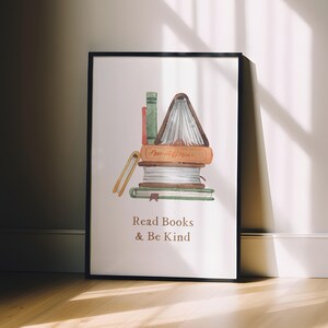 A framed poster with a watercolor illustration of a stack of books, accompanied by the text "Read Books & Be Kind" on a white background.