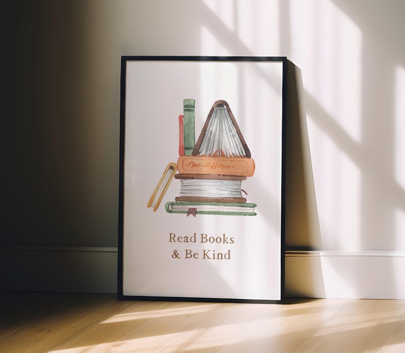 A framed poster with a watercolor illustration of a stack of books, accompanied by the text "Read Books & Be Kind" on a white background.