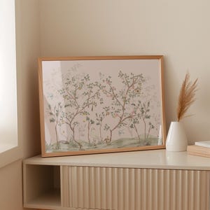 a framed painting of a tree with birds on a shelf, accompanied by a white vase with dried flowers.