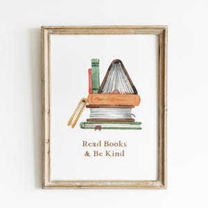 The image is a framed print with a watercolor illustration of a stack of books, accompanied by the text "Read Books & Be Kind" below the illustration.