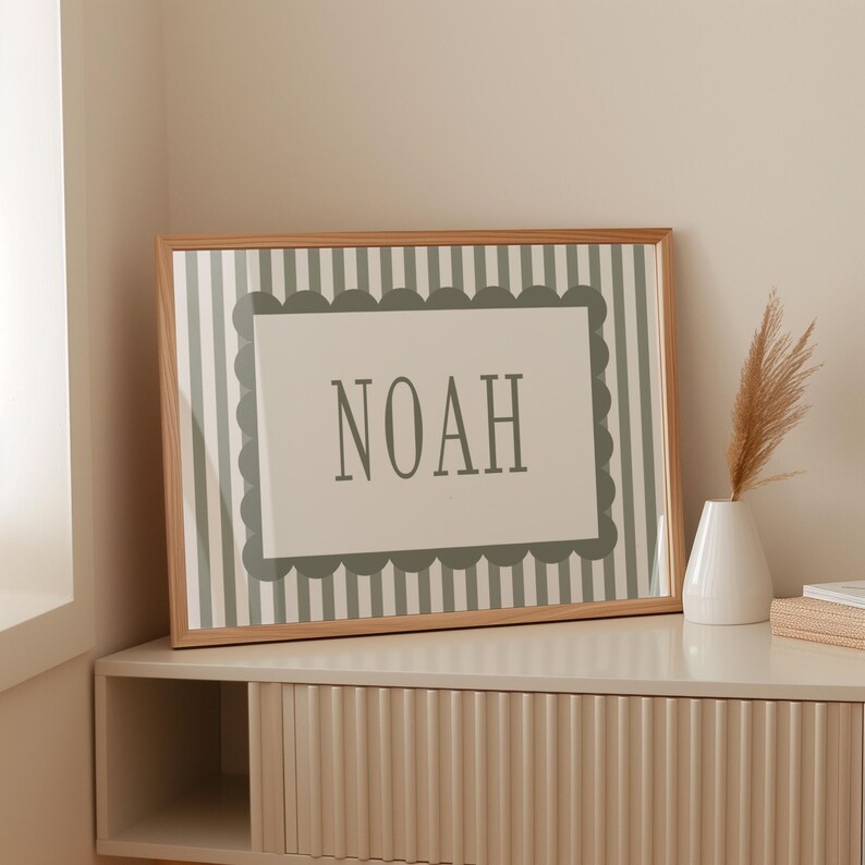 A framed picture with the word "NOAH" displayed on it, placed on a shelf next to a vase with dried flowers.