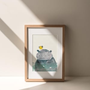 A framed illustration of a hippopotamus with a yellow flower on its head is displayed on a white wall.