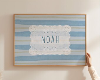May include: A framed wall art piece featuring the name "NOAH" in blue letters. The background has blue and light green horizontal stripes. The name is displayed on a white, scalloped-edge design.
