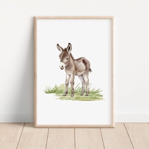 May include: A watercolor painting of a brown and white donkey standing on a green grassy patch. The donkey is facing the left side of the image and has its head tilted down.