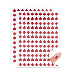 May include: A sheet of small, circular stickers featuring a repeating pattern of red ladybugs with black spots on a white background. Each ladybug has a distinct black head and antennae. One individual ladybug sticker is shown peeled off the sheet.