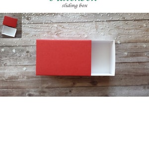 May include: Red matchbox style sliding box with a white interior. The box is open and the lid is off.