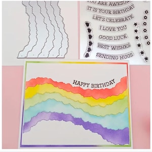 Puede incluir: Una tarjeta con un dise&ntilde;o de acuarela de arco&iacute;ris y el texto "Happy Birthday" en ella. La tarjeta est&aacute; rodeada de sellos transparentes con varios mensajes, incluyendo "It is your birthday", "Let's celebrate", "I love you", "Good luck", "Best wishes", y "Sending hugs".