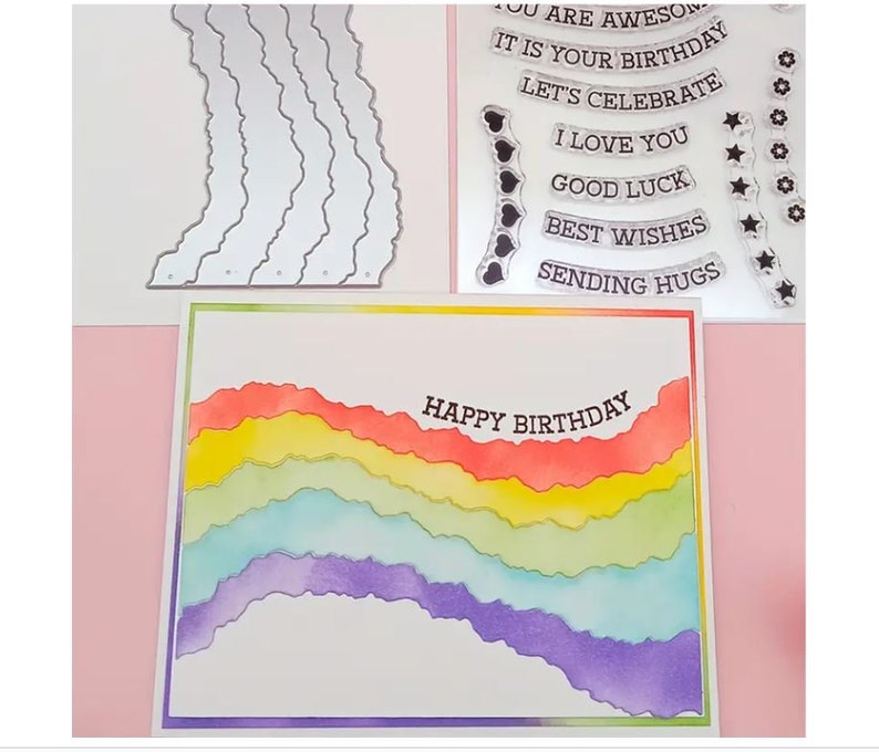 Puede incluir: Una tarjeta con un dise&ntilde;o de acuarela de arco&iacute;ris y el texto "Happy Birthday" en ella. La tarjeta est&aacute; rodeada de sellos transparentes con varios mensajes, incluyendo "It is your birthday", "Let's celebrate", "I love you", "Good luck", "Best wishes", y "Sending hugs".