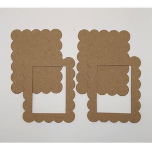 May include: Two sets of brown, scalloped-edge picture frames and inserts. The frames have a square opening and are made of a light brown cardboard material. The inserts are also scalloped and fit inside the frames. The background is white.
