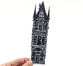 May include: Black and white illustration of a gothic bookstore building with the text "Gothic Grimoires Book Emporium" above the entrance. The building has a tall, pointed roof and many windows.