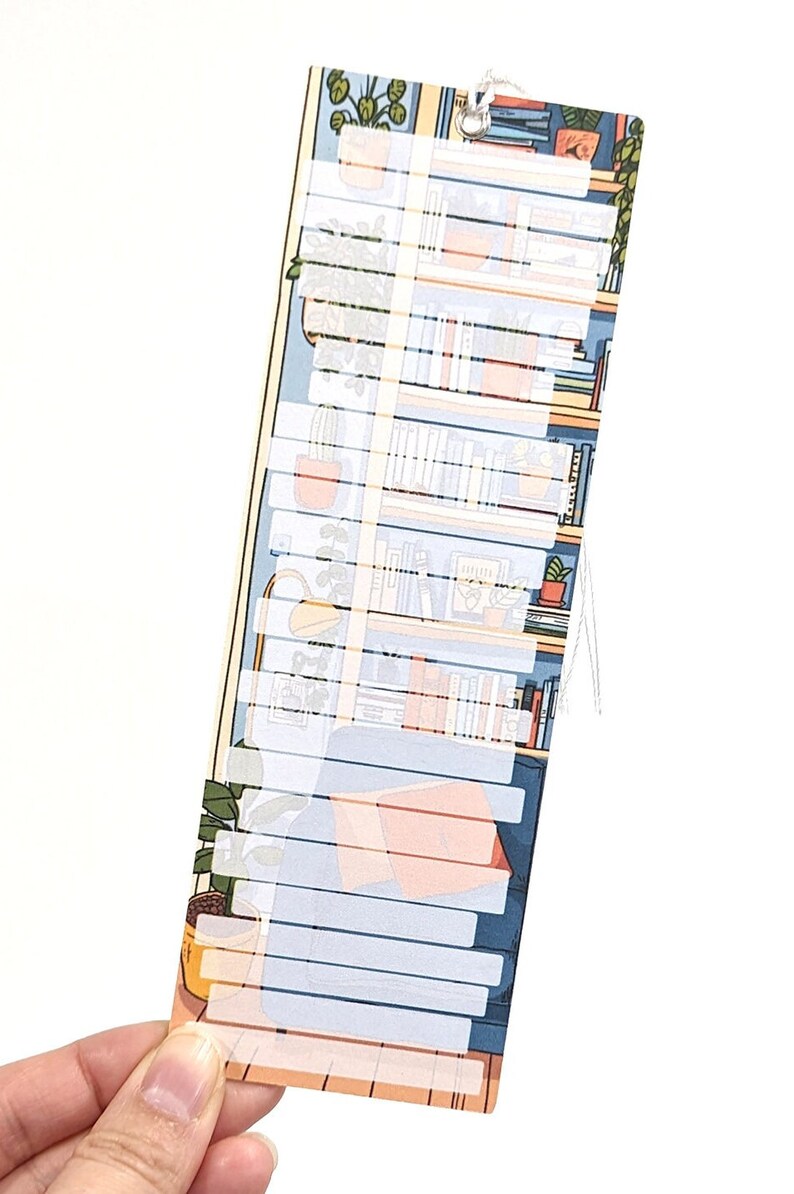 Pode incluir: Um marcador azul e amarelo com um design de estante de livros e plantas. O marcador tem uma se&ccedil;&atilde;o branca com linhas para escrever.