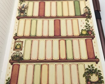 May include: A sticker sheet featuring four wooden shelves filled with blank book spines in shades of cream, sage green, and muted red. The design includes illustrations of potted plants, a frog in a terrarium, a framed frog portrait, and a small frog.