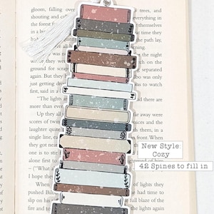 Puede incluir: Una pila de 42 lomos de libros con un marcap&aacute;ginas de borla blanca. El marcap&aacute;ginas est&aacute; decorado con una pila de libros de varios colores y patrones. El texto "New Style: Cozy" y "42 Spines to fill in" est&aacute; impreso en el marcap&aacute;ginas.