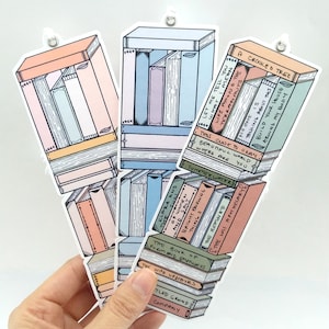 May include: Three colorful bookmarks with stacks of books and titles like "A Crooked Tree", "Summer Water", and "The Wife Upstairs".