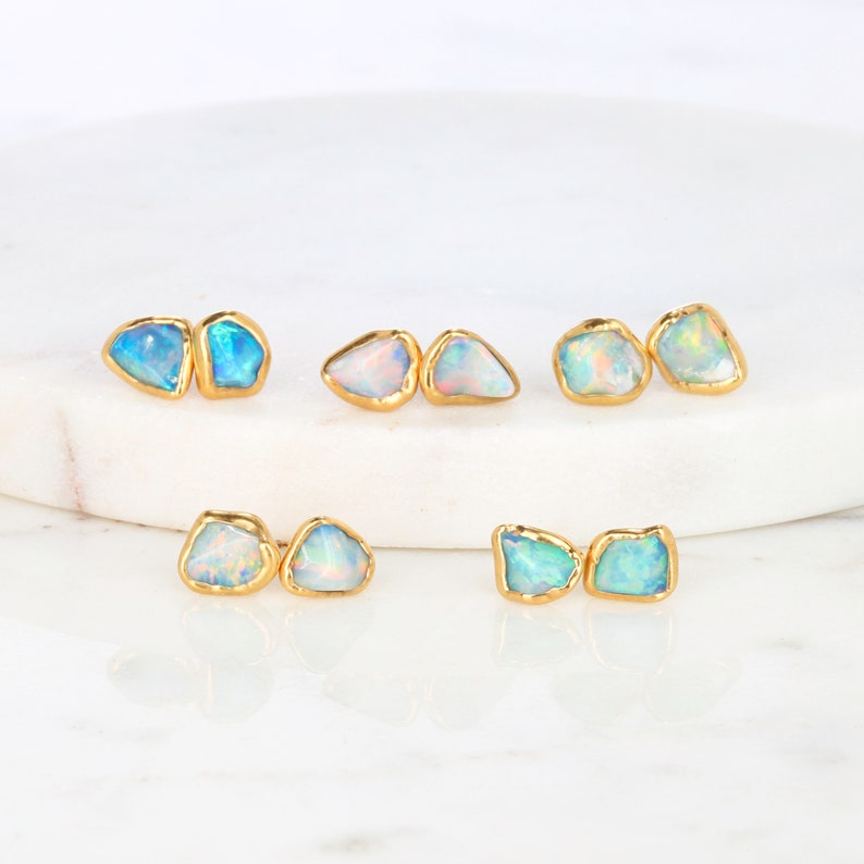 May include: Set of six gold-plated opal earrings. Each earring features two irregularly shaped opals with a light blue and white iridescent sheen.