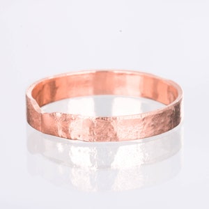 May include: A rose gold hammered band ring. The ring is simple and elegant, with a textured finish.