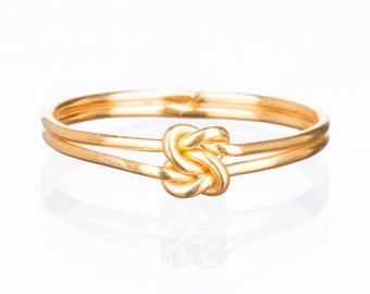 May include: A gold-toned ring with a double band and a knot design.