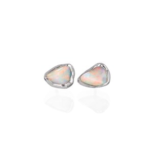 May include: A pair of silver earrings featuring white opal stones. The stones are irregularly shaped and have a raw, natural look.