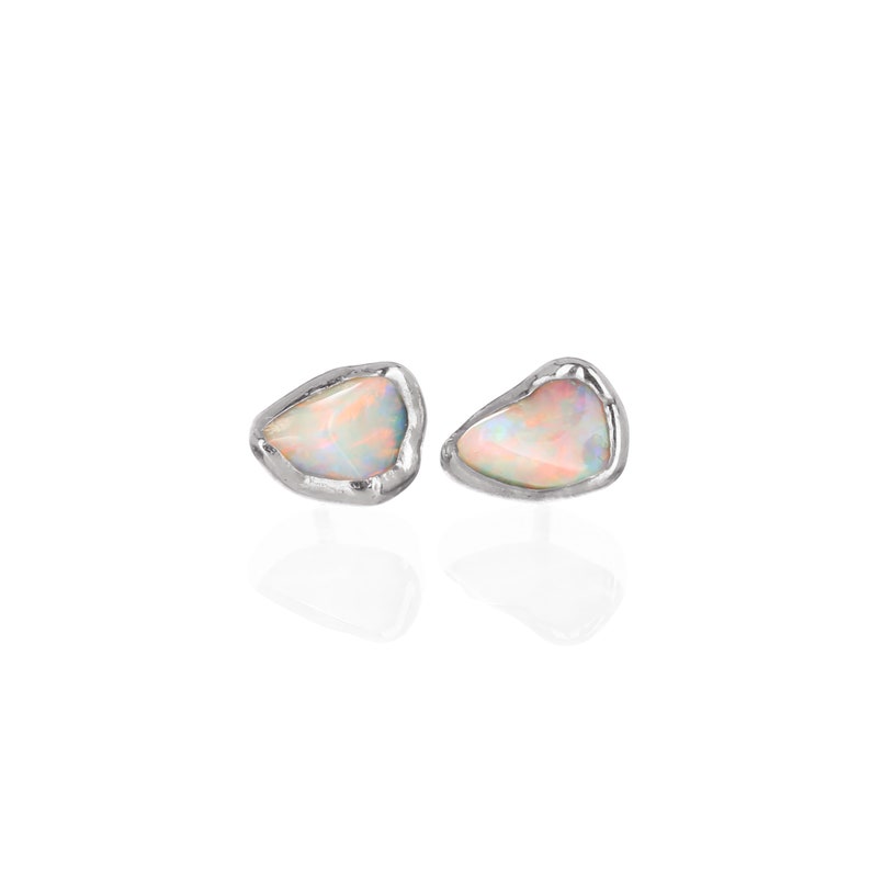 May include: A pair of silver earrings featuring white opal stones. The stones are irregularly shaped and have a raw, natural look.