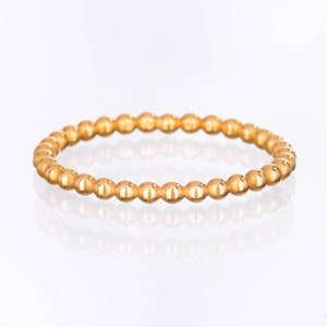 May include: A gold beaded ring with a smooth, polished finish. The ring is made of small, round beads that are evenly spaced.