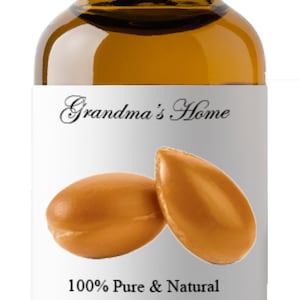 May include: A brown glass bottle with a black cap and a white label. The label says "Grandma's Home" and "100% Pure & Natural Argan Oil Argania spinosa". There are two brown argan nuts on the label.