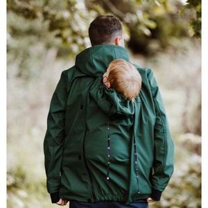 Puede incluir: Una chaqueta verde oscuro con un portabeb&eacute;s integrado. La chaqueta tiene una capucha y una cremallera. El portabeb&eacute;s es visible a trav&eacute;s de la parte posterior de la chaqueta.