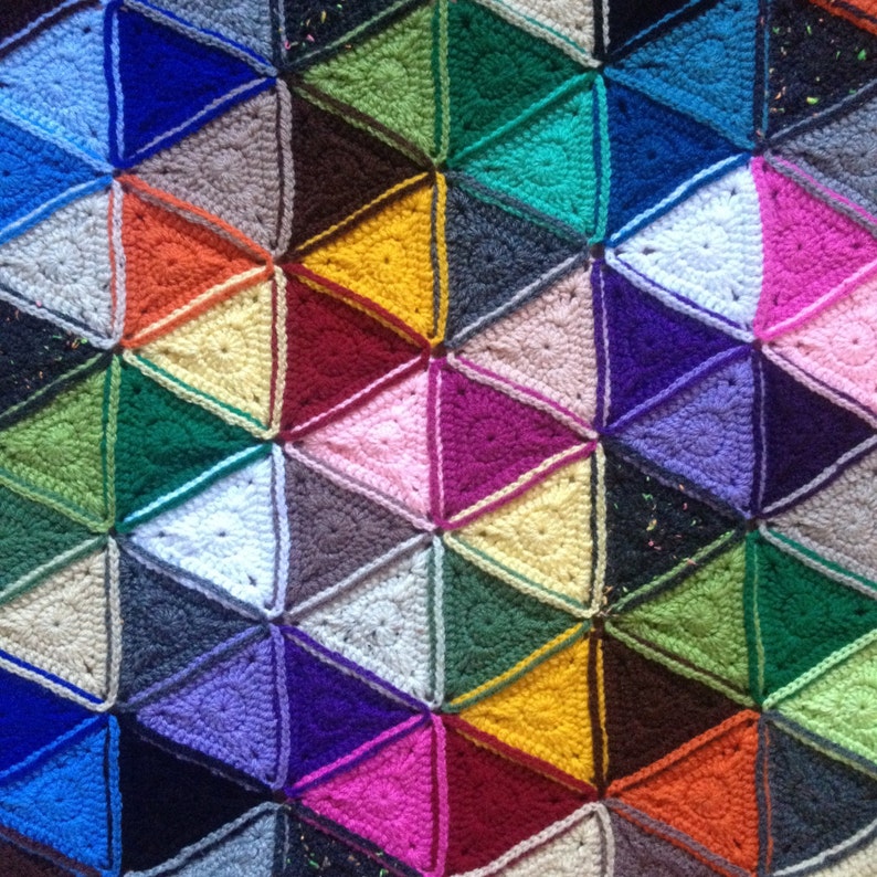 May include: A colorful crocheted blanket with a geometric pattern of triangles in various colors, including pink, purple, blue, green, yellow, and orange.