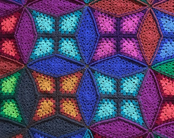 May include: A colorful crocheted blanket with a geometric pattern of stars and squares. The blanket is made with different shades of blue, green, purple, red, and orange yarn.