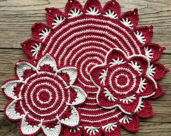 May include: Three crocheted doilies in red and white. The largest doily has a scalloped edge and a circular design. The two smaller doilies are flower-shaped.