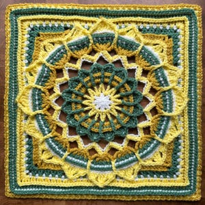 May include: A square, handmade crochet piece featuring a floral design. The piece uses yellow, green, and white yarn. The center is a white starburst, surrounded by a green floral pattern. The outer edges are yellow and green, creating a vibrant, textured textile.