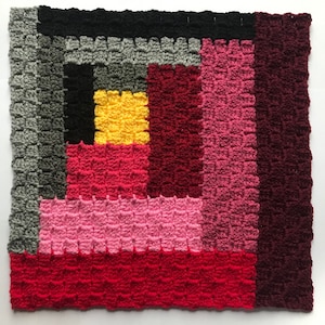 Puede incluir: Un cuadrado tejido a crochet con un diseño de patchwork. El cuadrado está formado por cuadrados de diferentes colores, incluyendo rojo, rosa, amarillo, negro y gris.