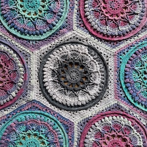 Puede incluir: Una manta hexagonal de ganchillo con un patrón repetitivo de diseños de mandalas coloridos. La manta está hecha con una variedad de tonos de hilo morado, rosa, turquesa y gris.