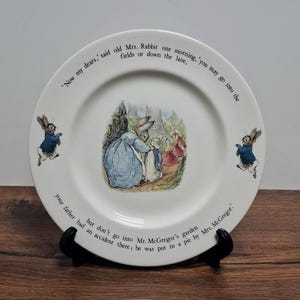 May include: A white ceramic mug with a black handle and the text "But First, Coffee" in a black, handwritten-style font. The mug is on a white surface.