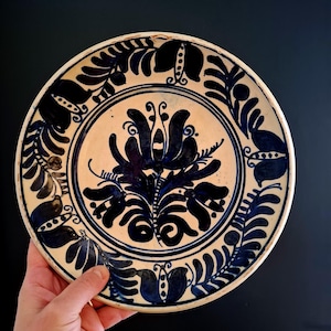 Op de afbeelding: Een witte keramische mok met een zwart handvat en de tekst "But First, Coffee" in handschriftstijl. De mok staat op een wit oppervlak. De mok is ongeveer 10 cm hoog.