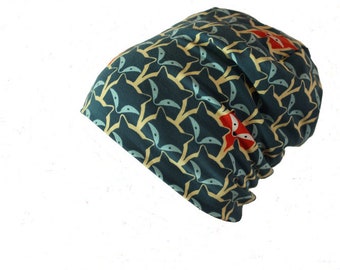 Op de afbeelding: Een tealblauwe beanie met een herhalend patroon van gestileerde vossenkoppen in geel en rood.