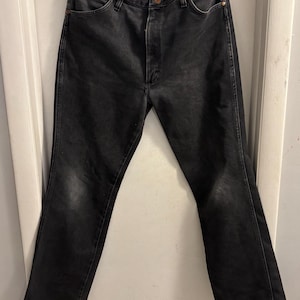 May include: Black denim jeans with a classic five-pocket design. The jeans have a button and zip closure, and a faded appearance. The jeans are a straight-leg style.