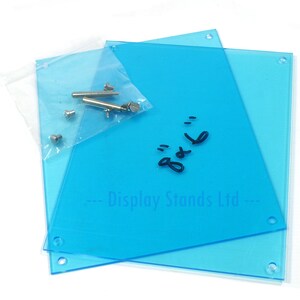 May include: Two clear blue acrylic display stands with holes in the corners. A small bag of hardware is included. The stands are labeled "Display Stands Ltd."