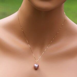 May include: A gold chain necklace with a single large, round, iridescent pearl pendant.