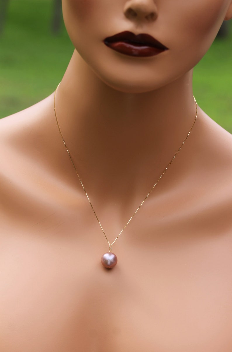 May include: A gold chain necklace with a single large, round, iridescent pearl pendant.