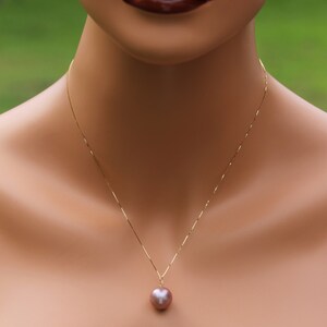 May include: A gold chain necklace with a single large, round, iridescent pearl pendant.