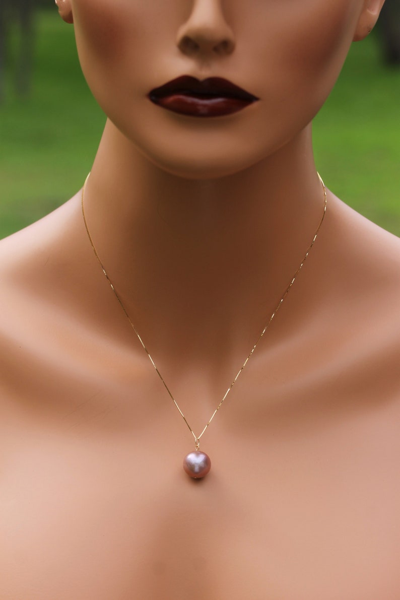 May include: A gold chain necklace with a single large, round, iridescent pearl pendant.