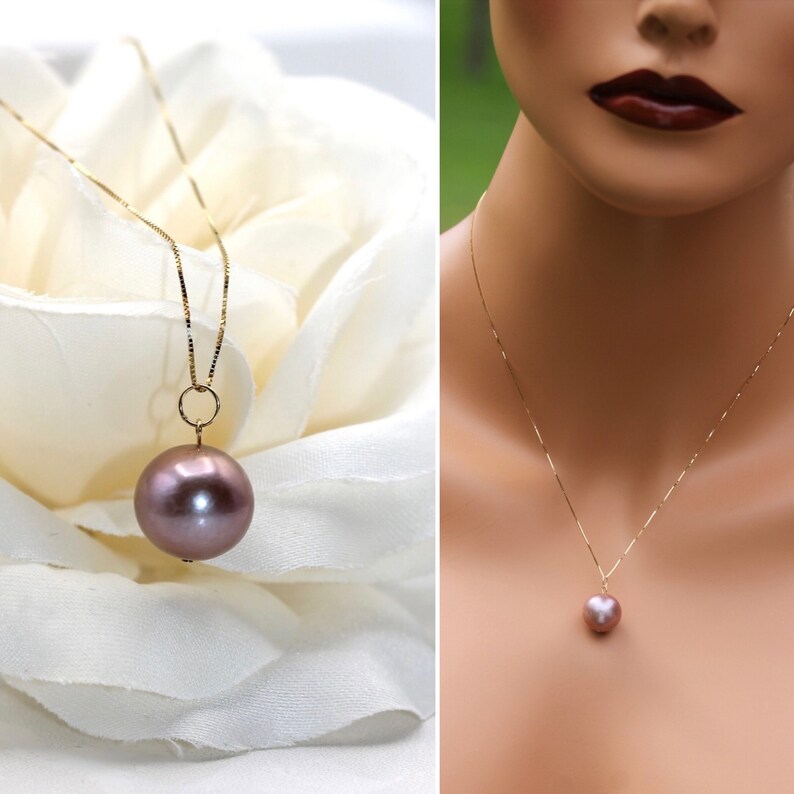 May include: A delicate gold chain necklace with a single, large, round, mauve-colored pearl pendant.