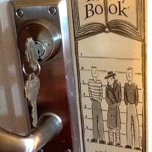 May include: A brown and white sign with the text "In my Book" and a drawing of a book. The sign also has a line-up of three cartoon characters with the text "you're the one who didn't!" at the bottom.