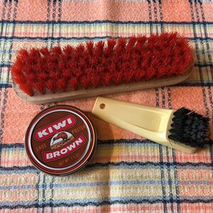 Puede incluir: Un cepillo rectangular de madera con cerdas rojas rígidas, una lata redonda de metal de betún marrón Kiwi con un peso neto de 32g, y un cepillo pequeño de plástico color crema con cerdas negras para aplicar el betún para calzado.