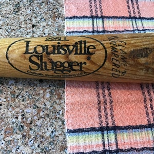 Pu&ograve; includere: Una mazza da baseball in legno Louisville Slugger con lettere nere che recitano "Louisville Slugger" e "25U" con un ovale nero attorno al testo. La mazza ha anche lettere nere che recitano "Flame Tempered" sul lato.