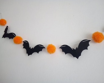 May include: A Halloween garland featuring black bats and orange pom-poms.